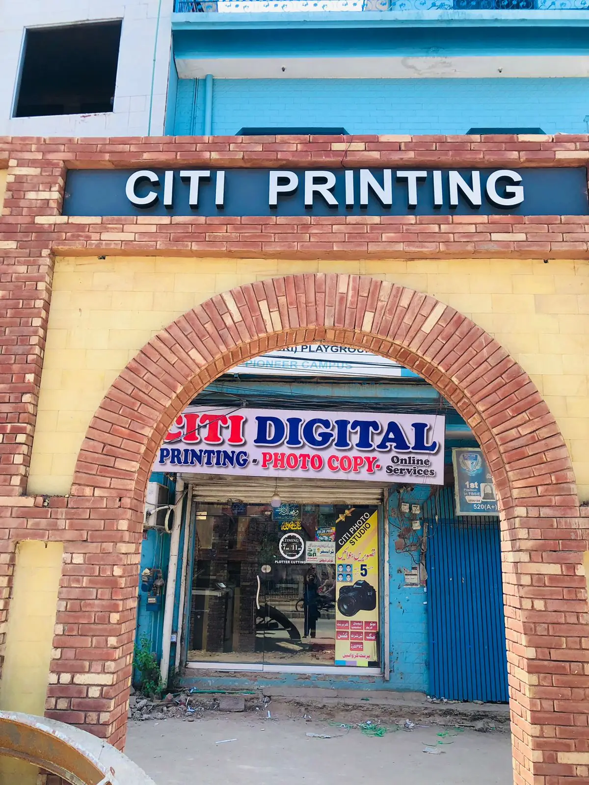 Citi Digital shopfront under the brick arch: Printing, Photo Copy, Online Services sign, Citi Photo Studio poster and the 7 to 11 timing sticker